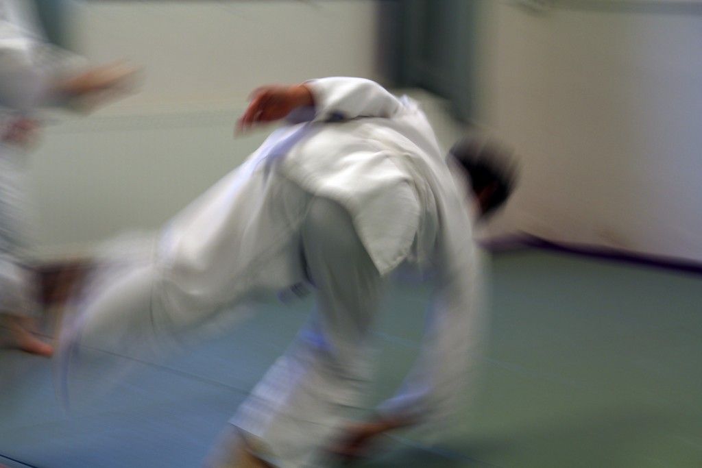 Hod během tréninku aikidó na tatami, zachycený v pohybu