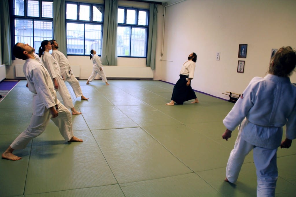 Skupina cvičenců v kimonech na tatami při společném cvičení